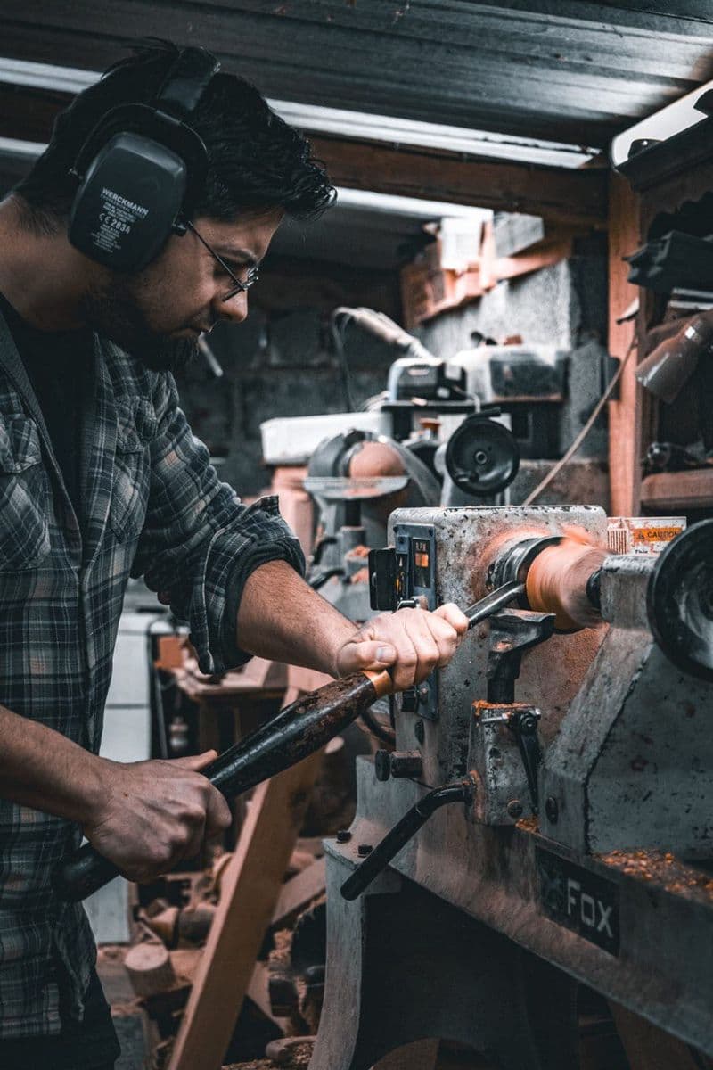 Stagiaire au tour à bois dans l'atelier
